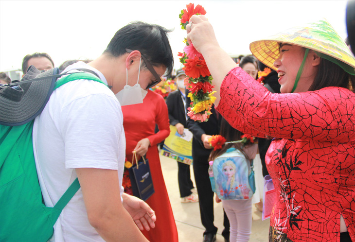This image shows a member of the group of 120 South Korean tourists being offered flowers by a local receptionist when they arrived in Khanh Hoa Province, in south-central Vietnam, on January 1, 2023. Photo: Minh Chien / Tuoi Tre