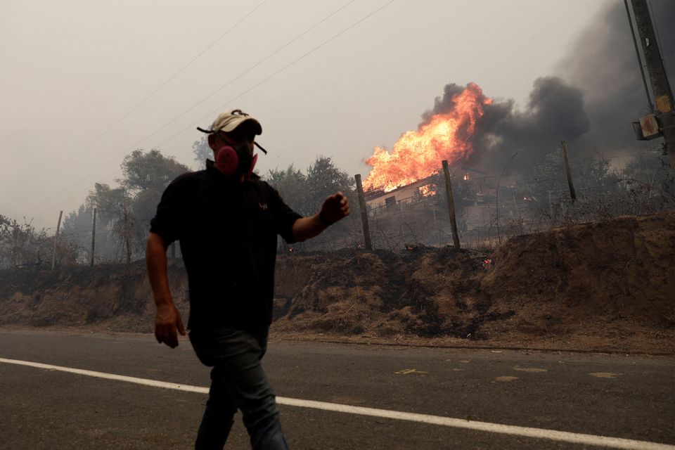 A local resident walks past as a wildfire in Santa Juana, near Concepcion, Chile, February 3, 2023. Photo: Reuters