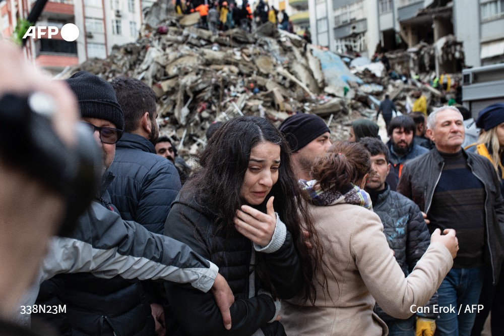 A woman is helped away as rescuers search for survivors in the rubble of collapsed buildings in Adana, southwest Turkey, on February 6, 2023. Photo: AFP
