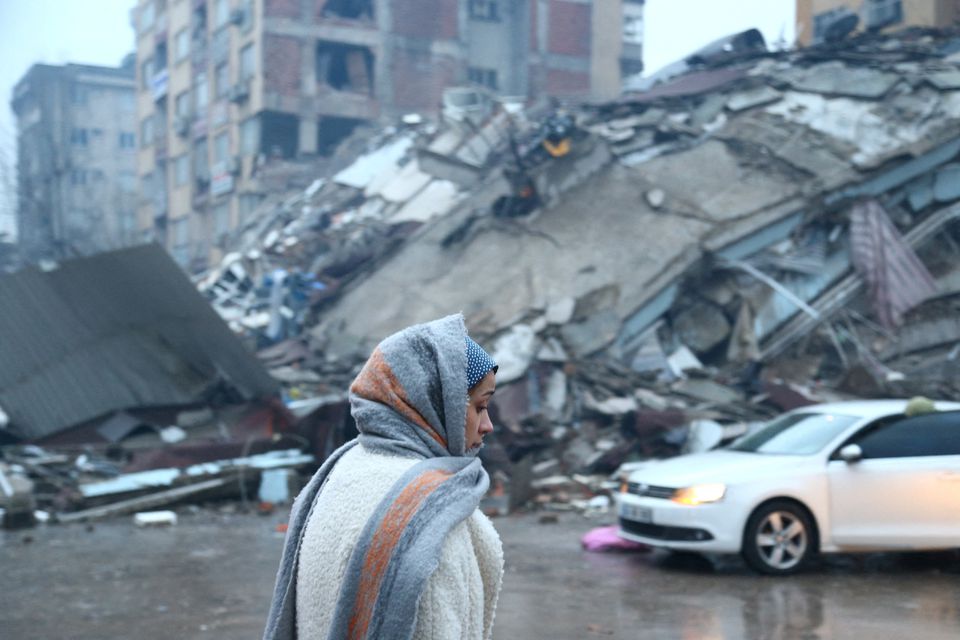 A woman stands near a collapsed building after an earthquake in Kahramanmaras, Turkey February 6, 2023. Photo: Reuters
