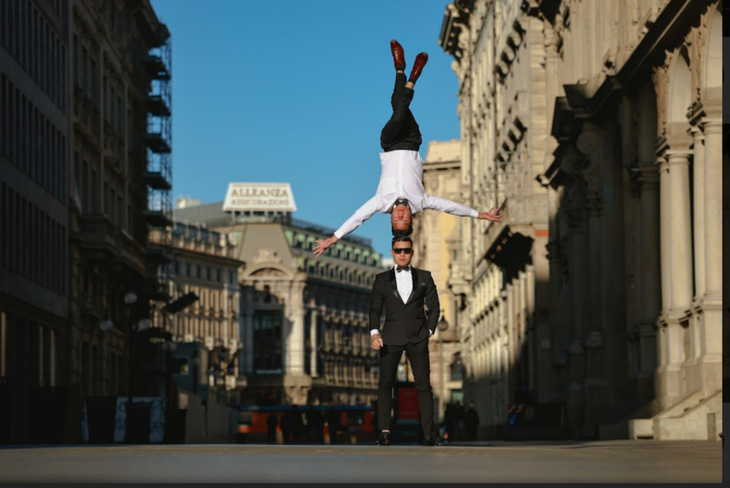 This image shows the Vietnamese acrobatic duo performing their head-to-head balancing walk outside the ancient Giureconsulti building in Milan, Italy. Photo: Hai An / Tuoi Tre