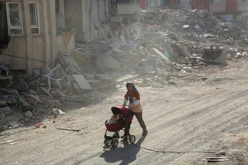 A woman pushes a baby carriage carrying her belongings, in the aftermath of the deadly earthquake, in Adiyaman, Turkey, February 12, 2023. Photo: Reuters