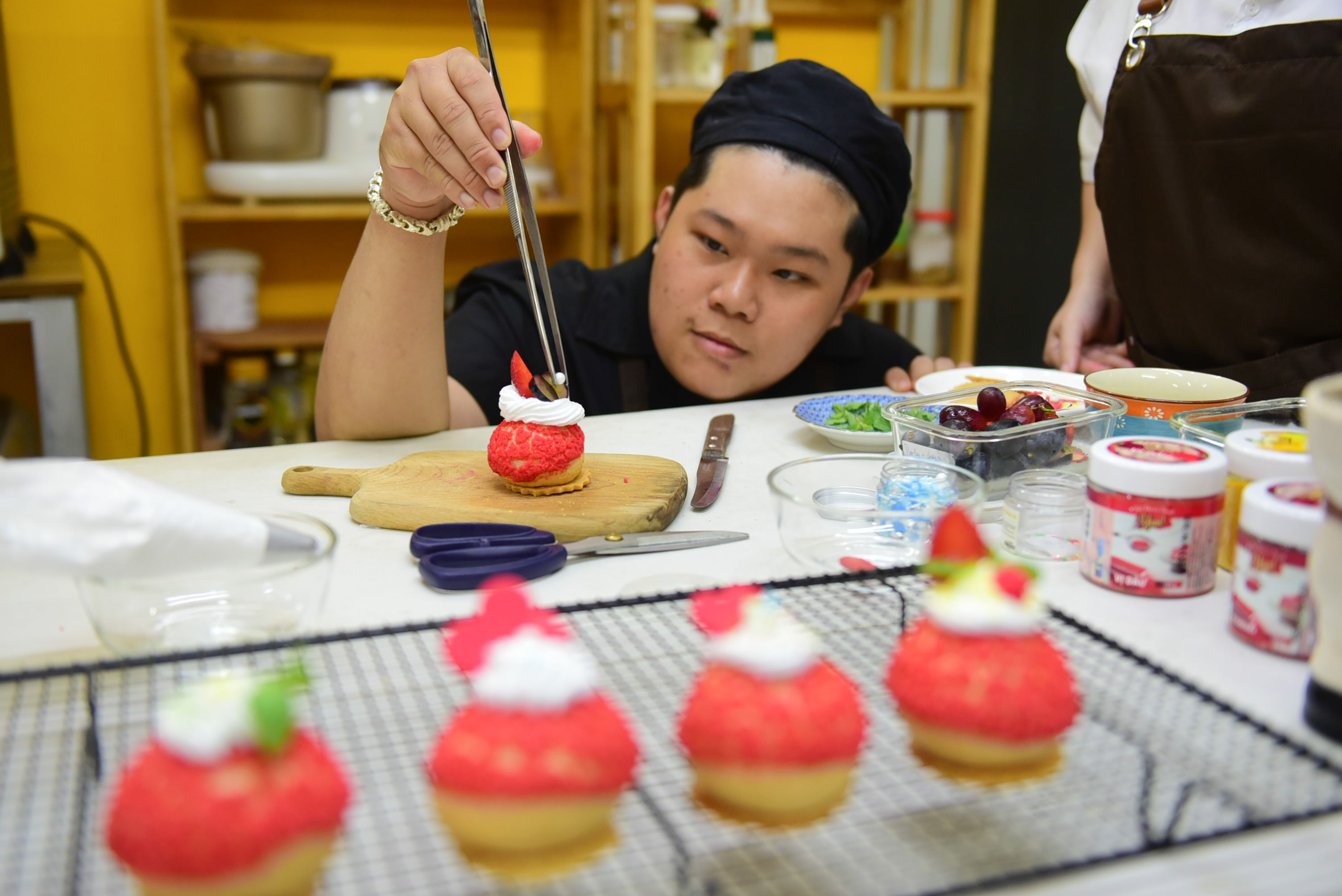 An attendee decorates Valentine Craquelin puffs he made at a baking workshop in Ho Chi Minh City  on the occasion of Valentine’s Day in 2023. Photo: Ngoc Phuong / Tuoi Tre News