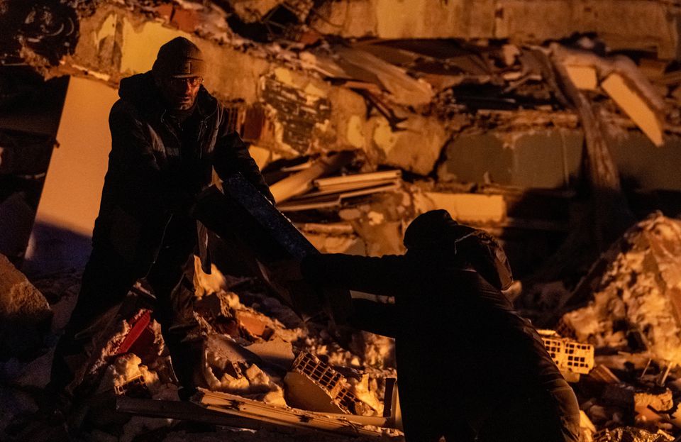 People gather boxes on the remains of a destroyed building in the aftermath of a deadly earthquake in Elbistan, Turkey February 14, 2023. Photo: Reuters