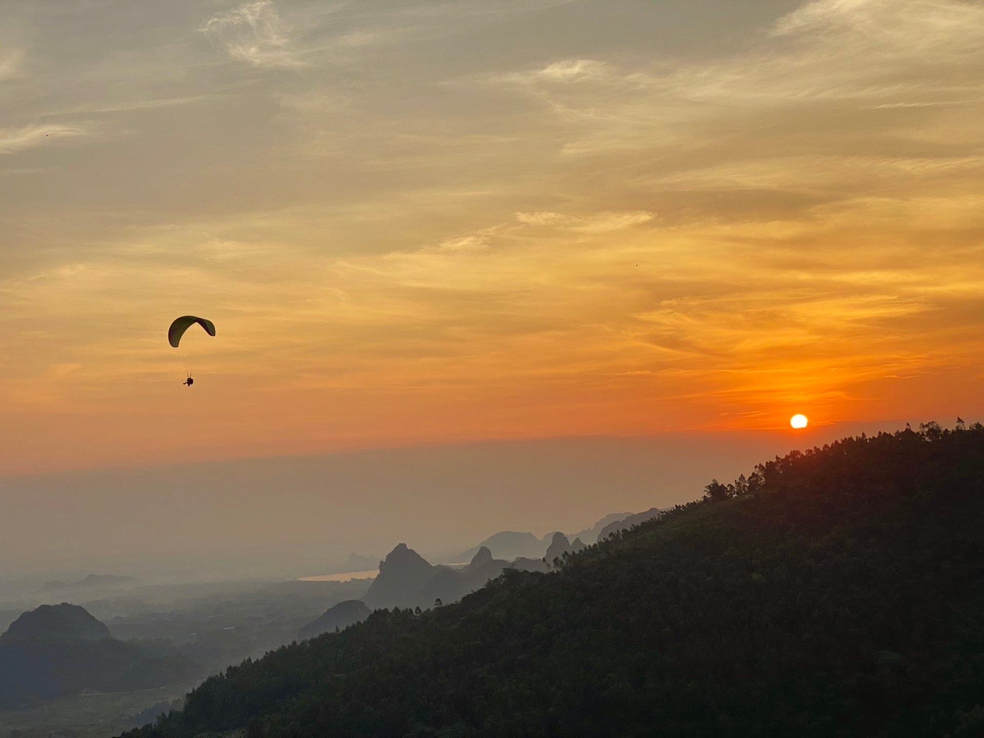 Paragliders fly under the sunset at Bu Hill on the outskirts of Hanoi, Vietnam. Photo by courtesy of Mebayluon