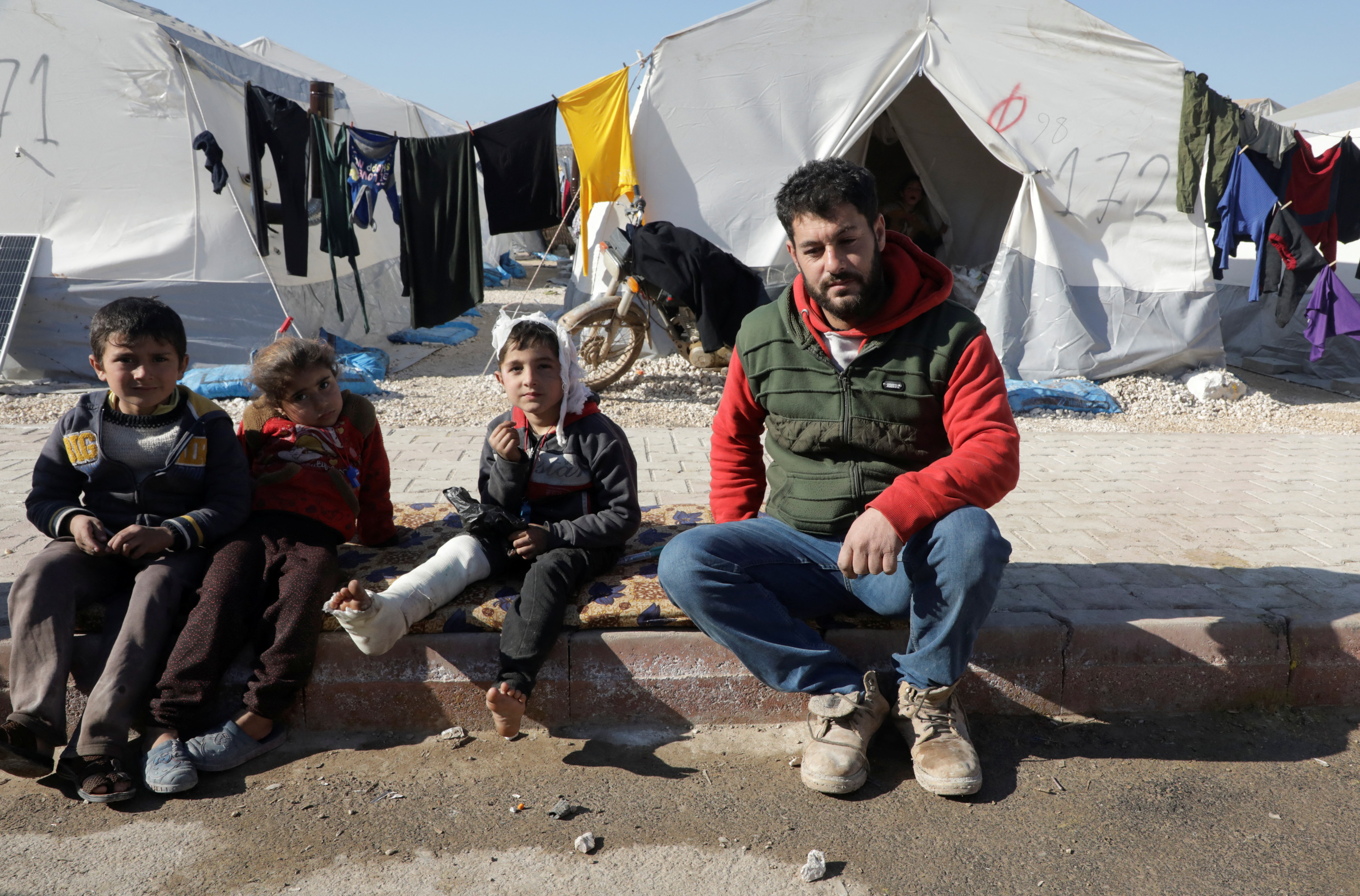 Displaced Syrian man, Omar Barakat, sits next to an injured child at a camp for earthquake survivors, on the outskirts of rebel-held town of Jandaris, Syria February 17, 2023. Photo: Reuters