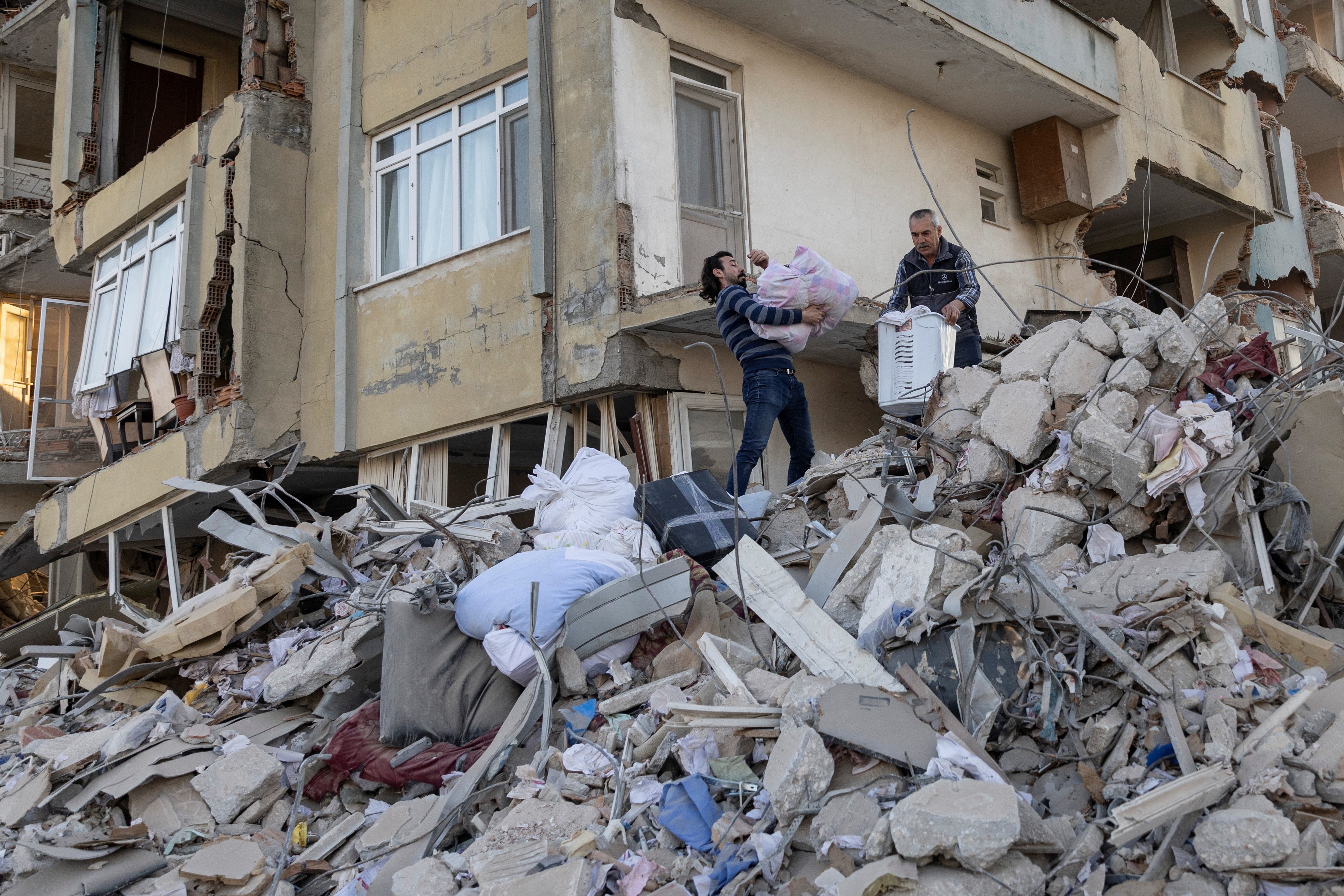 Arsin and his father take belongings out of their destroyed apartment in the aftermath of the deadly earthquake in Antakya, Hatay province, Turkey, February 20, 2023. Photo: Reuters