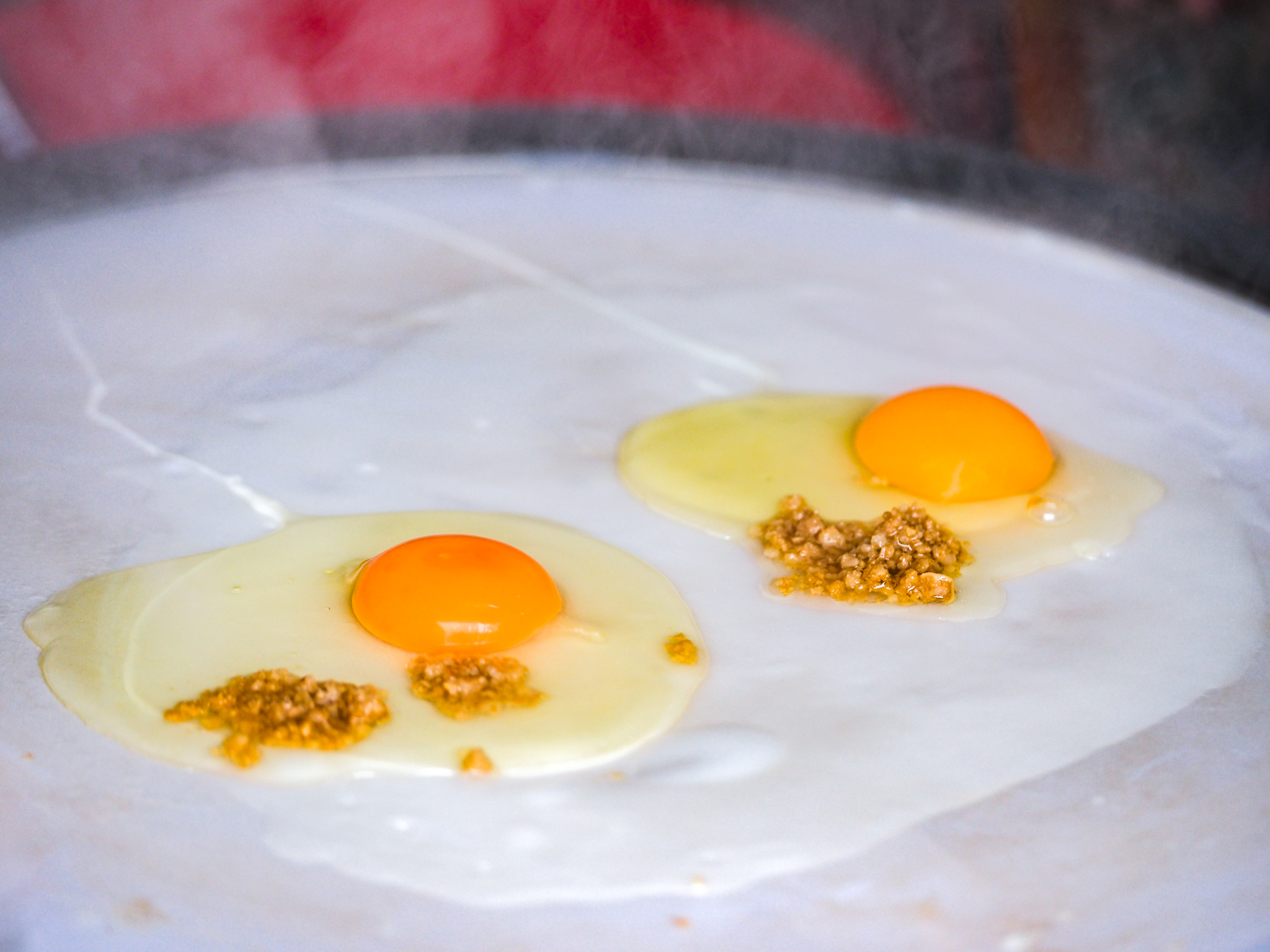 Eggs and minced pork are put on rice crepes to make rolls of banh cuon at Banh Cuon Cao Bang stall in Hanoi, Vietnam. Photo: Nam Tran / Tuoi Tre News