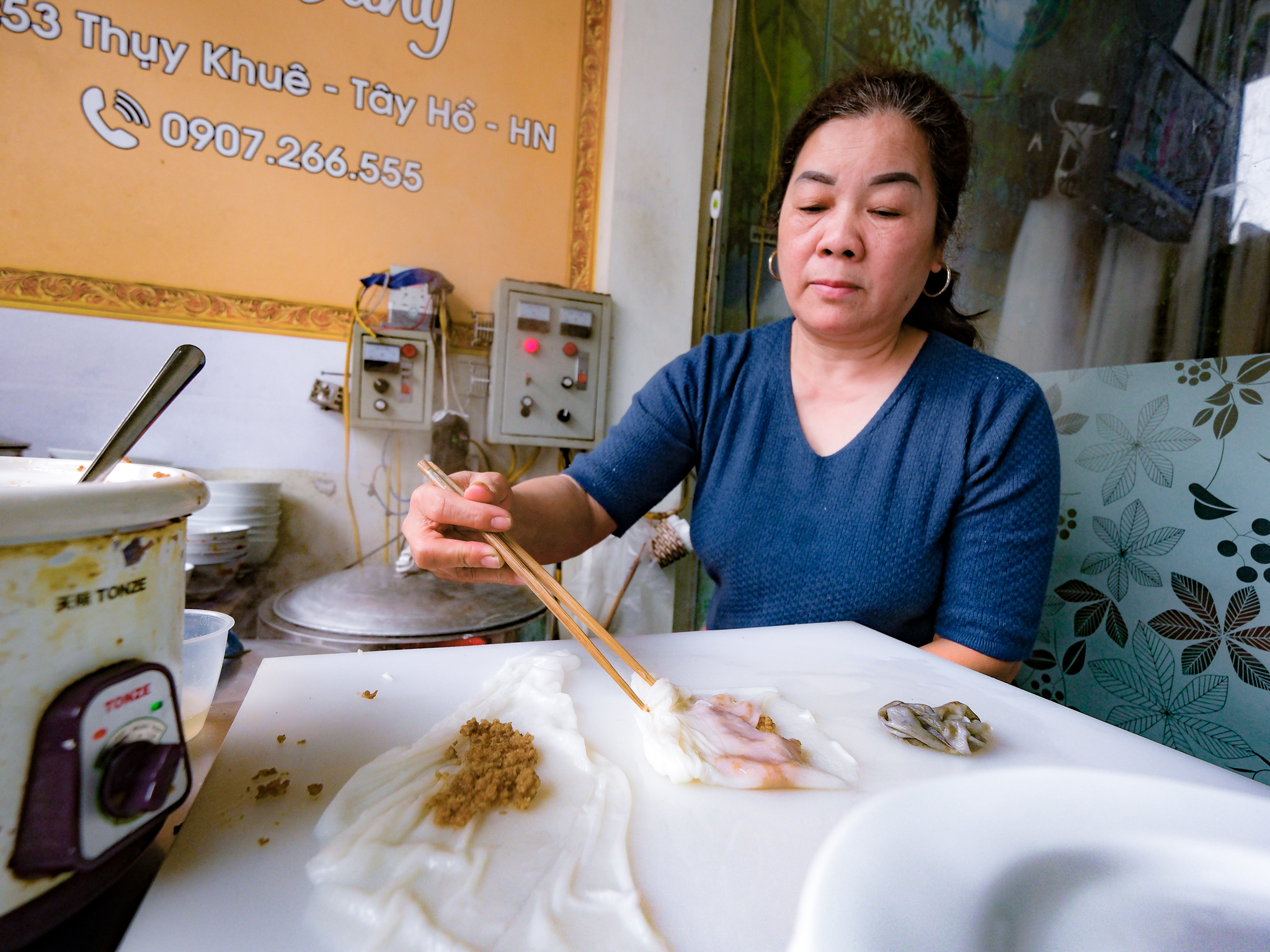 Dinh Thi Tam uses a pair of chopsticks to wrap the banh cuon. Photo: Nam Tran / Tuoi Tre