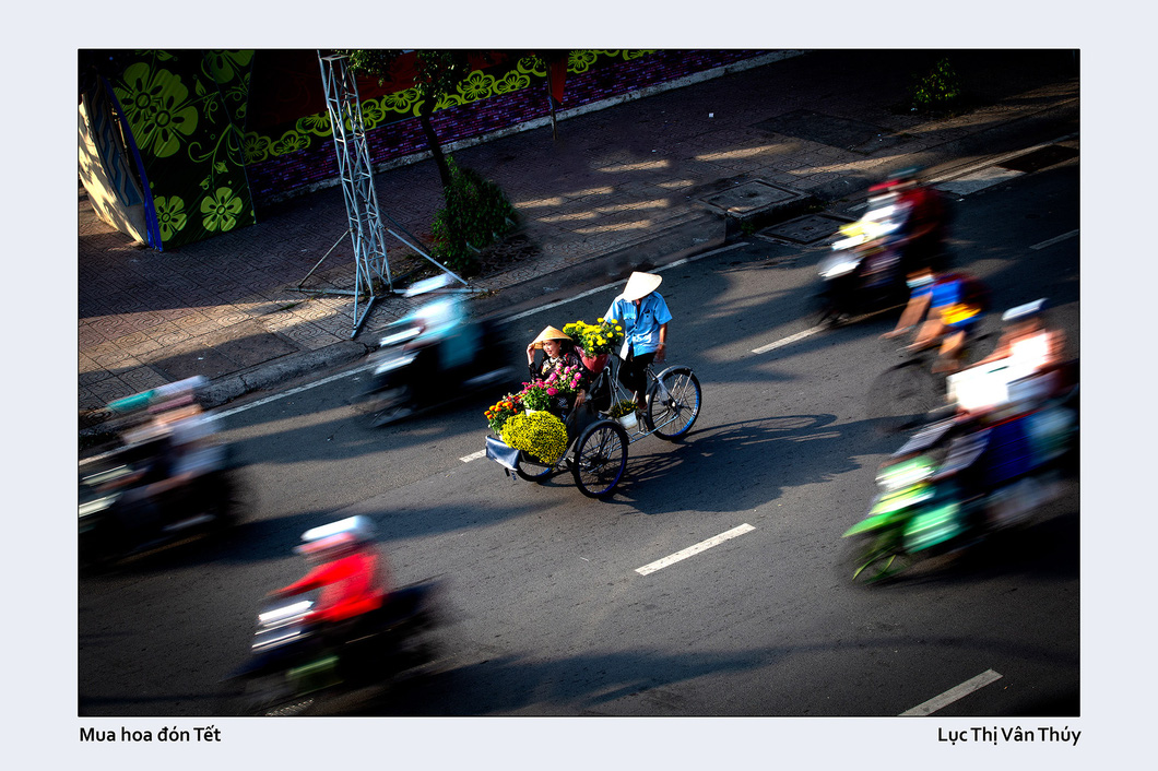 Luc Thi Van Thuy captures a cyclo taxi carrying a woman and flowers she bought for Tet (Lunar New Year) on Tran Hung Dao Street, District 5, Ho Chi Minh City.