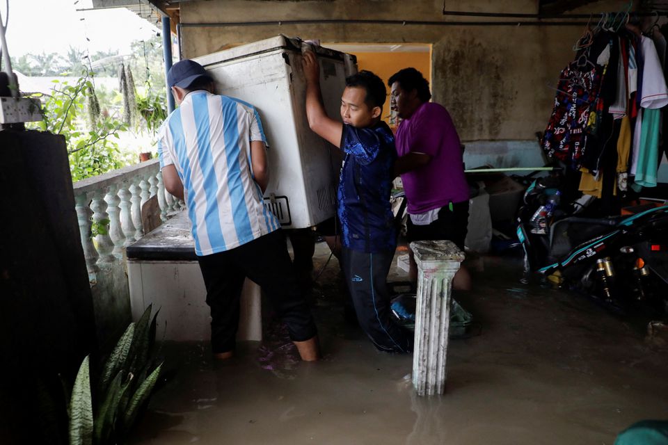 People move a refrigerator from a flooded house, during a flood at Yong Peng, Johor, Malaysia March 4, 2023. Photo: Reuters