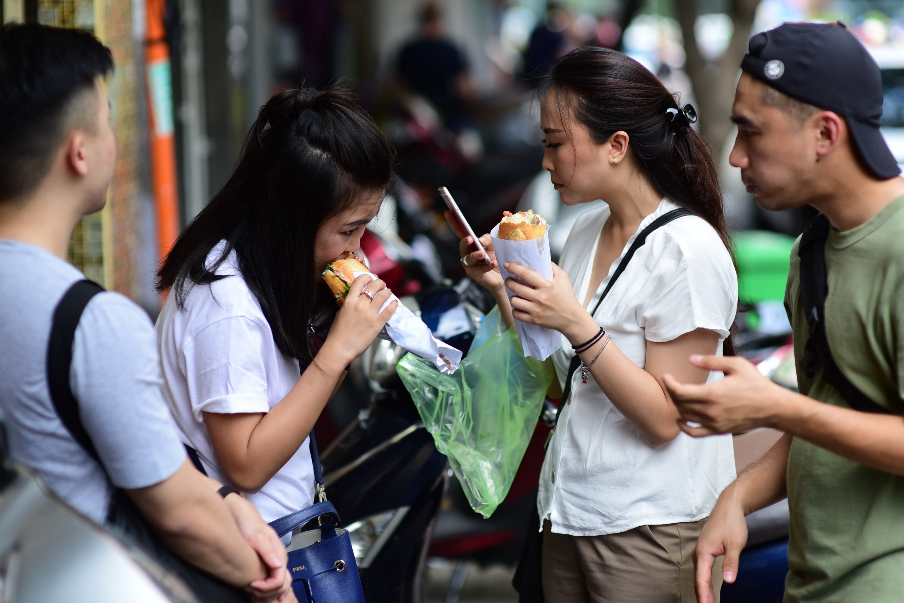 A file photo shows people enjoying banh mi on the street in Ho Chi Minh City. Photo: Quang Dinh / Tuoi Tre