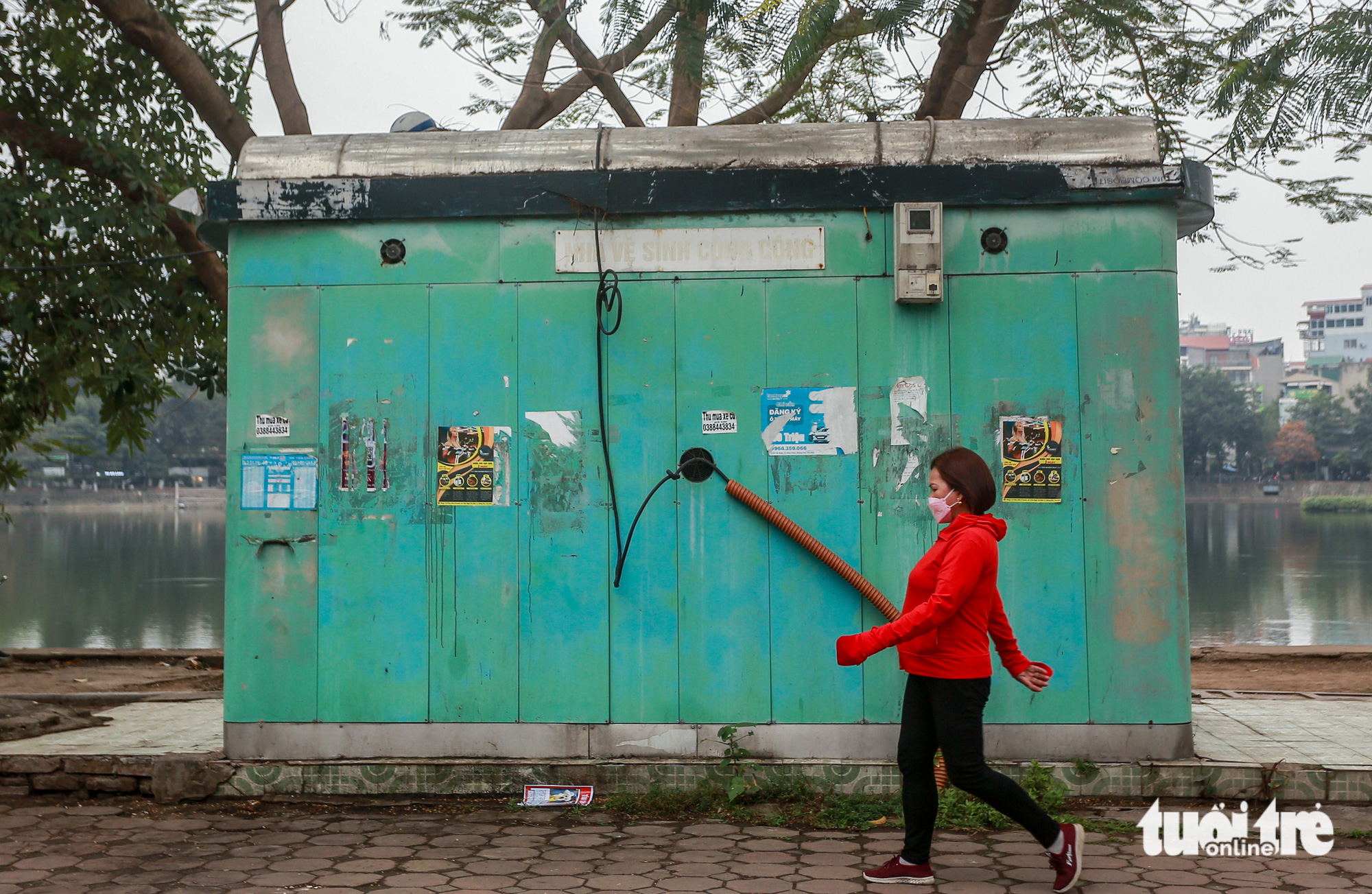 A woman walks past a degraded public restroom. Photo: Ha Quan/ Tuoi Tre