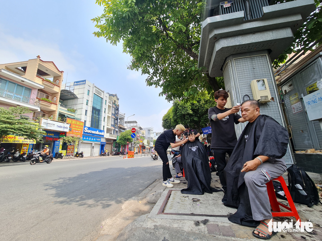 Barbers make the most of the sidewalk in front of the Ward 4 People’s Committee headquarters in Go Vap District, Ho Chi Minh City to offer the free haircut service due to an overwhelming amount of participants. Photo: Cong Trieu / Tuoi Tre