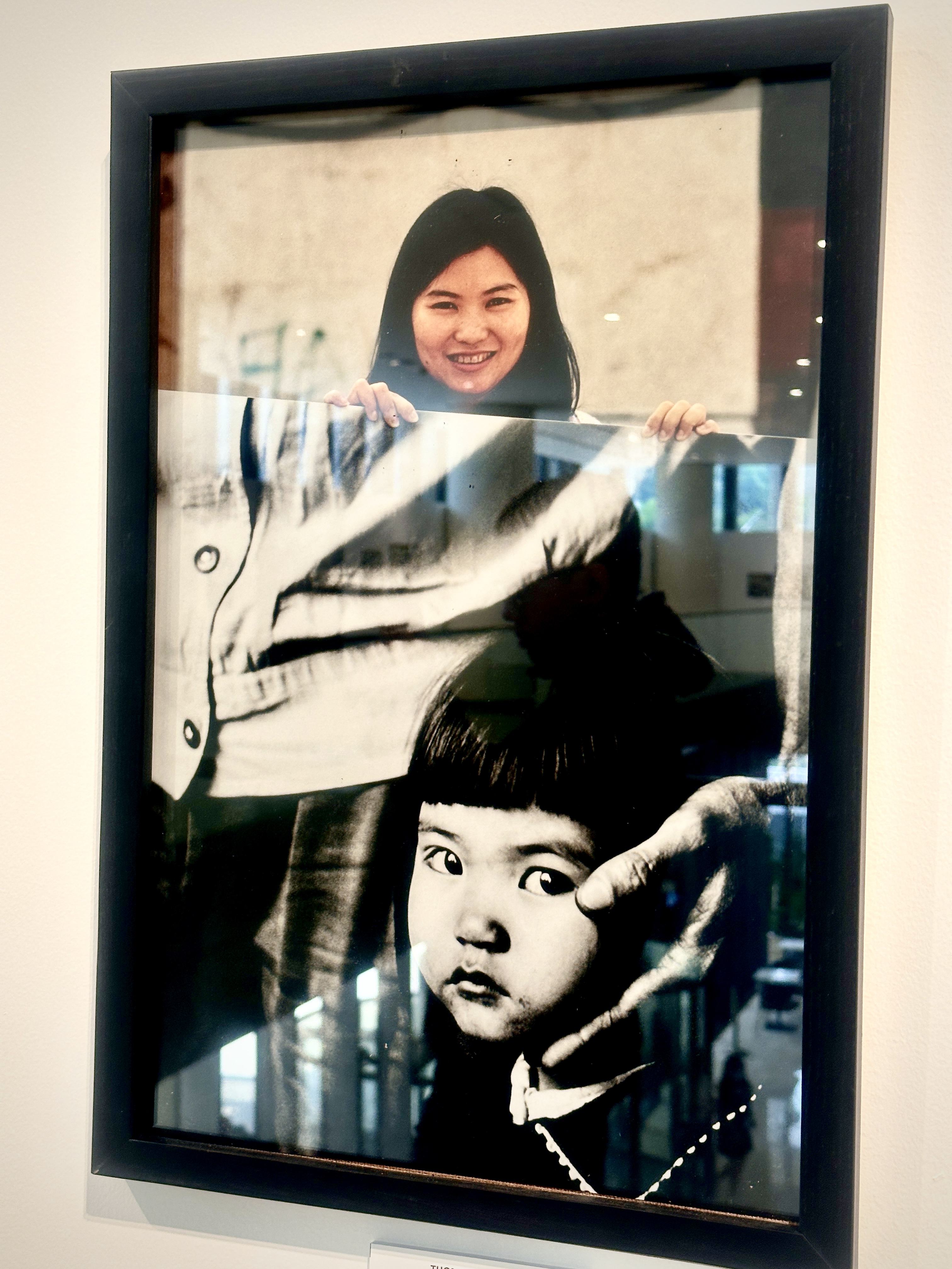 A photo of Dang Tran, 28, holding the photo of her being four years old captured by Thomas Billhardt in Hanoi in 1999 at the exhibition. Photo: Tieu Bac / Tuoi Tre News