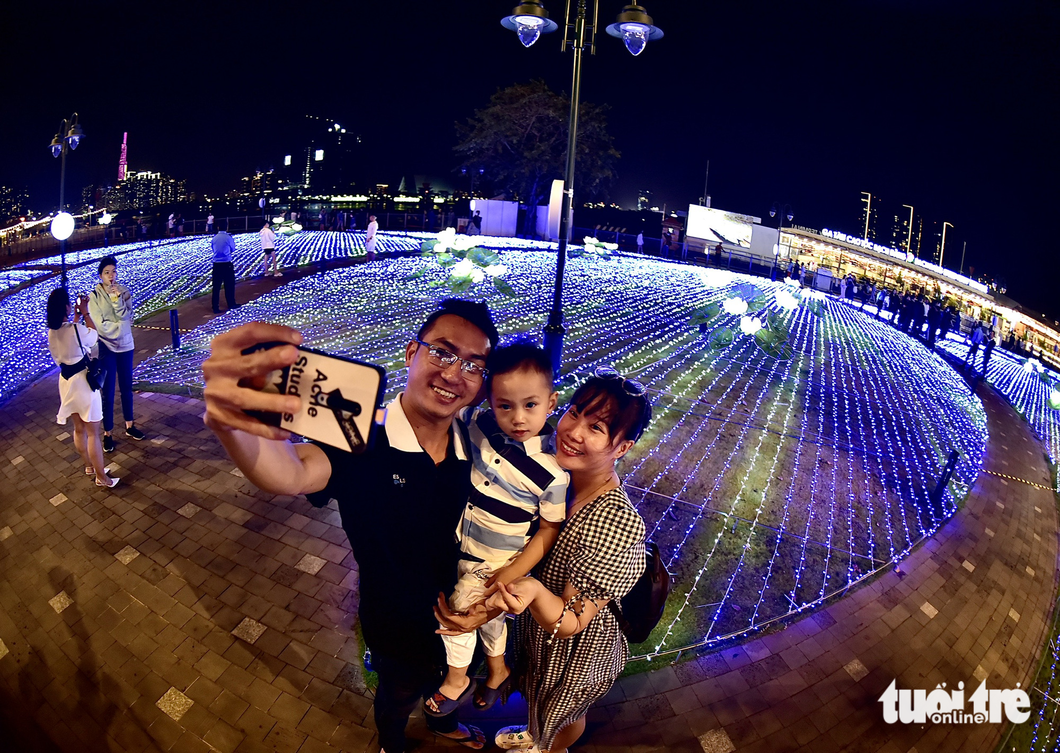 Tuan, a resident of Phu Nhuan District, Ho Chi Minh City, along with his family, takes selfies in the LED lotus field. Photo: T.T.D. / Tuoi Tre