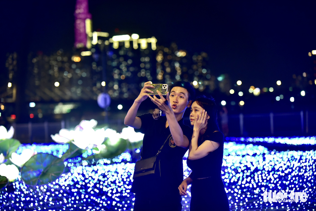 Two youngsters take selfies in the LED lotus field. Photo: T.T.D. / Tuoi Tre