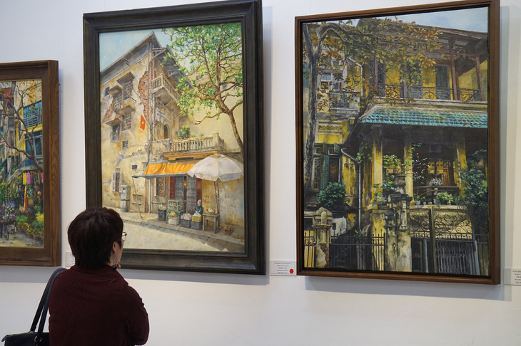 A visitor looks at Nam Long's paintings on display at the exhibition. Photo: Thien Dieu / Tuoi Tre