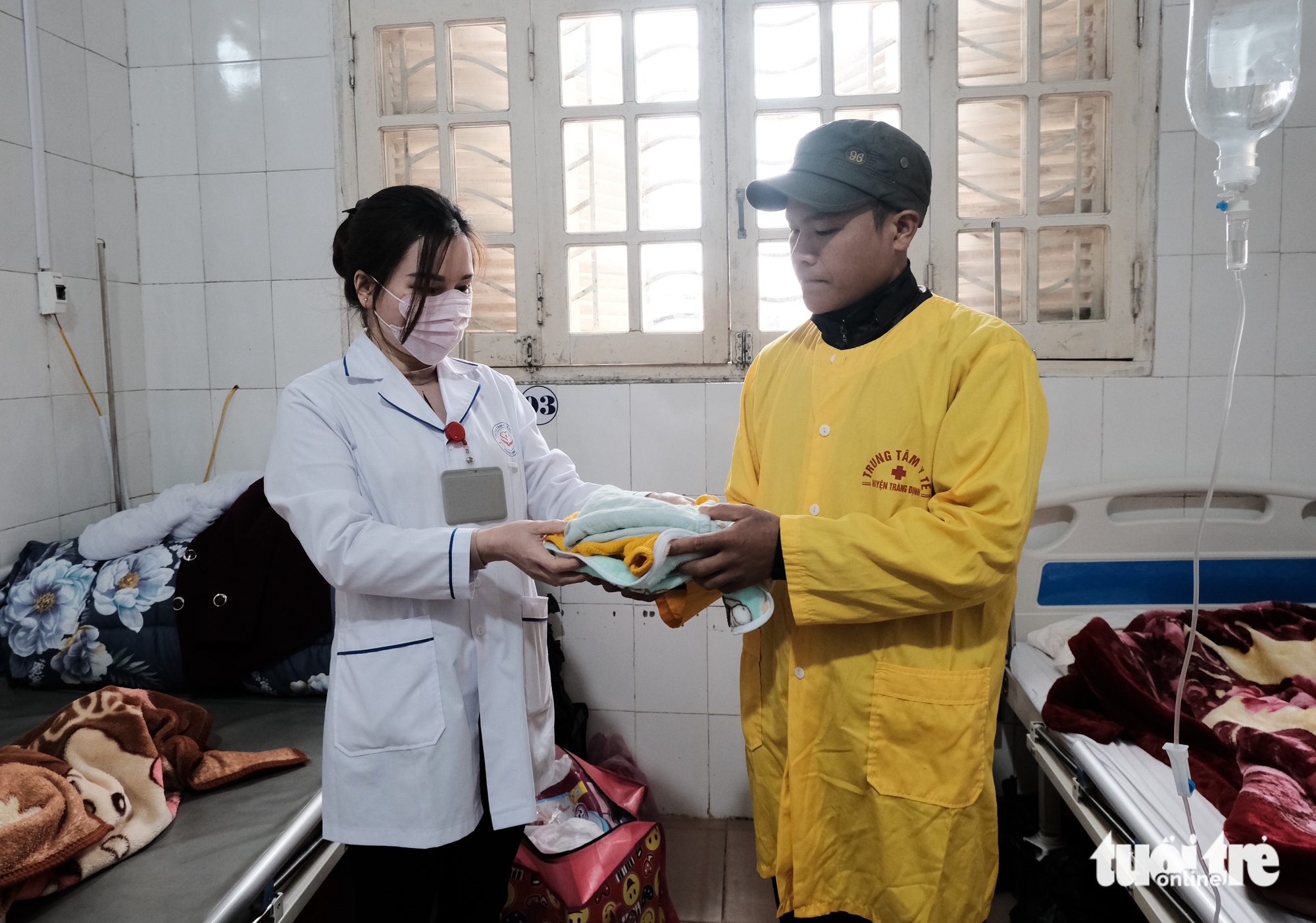 Van Anh, a nurse at the Trang Dinh General Hospital, gives clothes for a mother and her child to their family member. Photo: Ha Thanh / Tuoi Tre