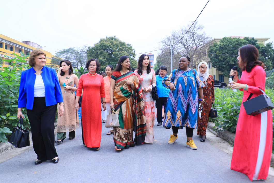 Vietnam’s Deputy Minister of Foreign Affairs Le Thi Thu Hang (wearing floral white-and-orange ao dai), diplomats, and the spouses of ambassadors visit local mulberry gardens. Photo: Tuoi Tre