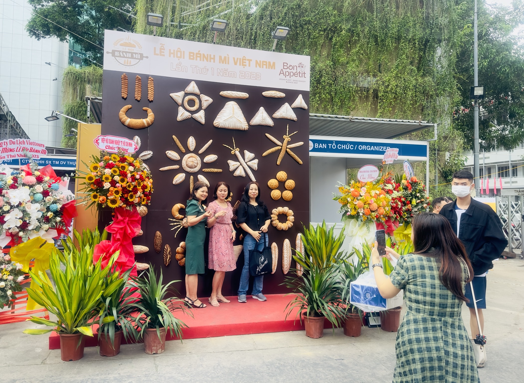 A woman takes a photograph of her friends with a picture decorated with loaves of banh mi. Photo: Tieu Bac / Tuoi Tre News