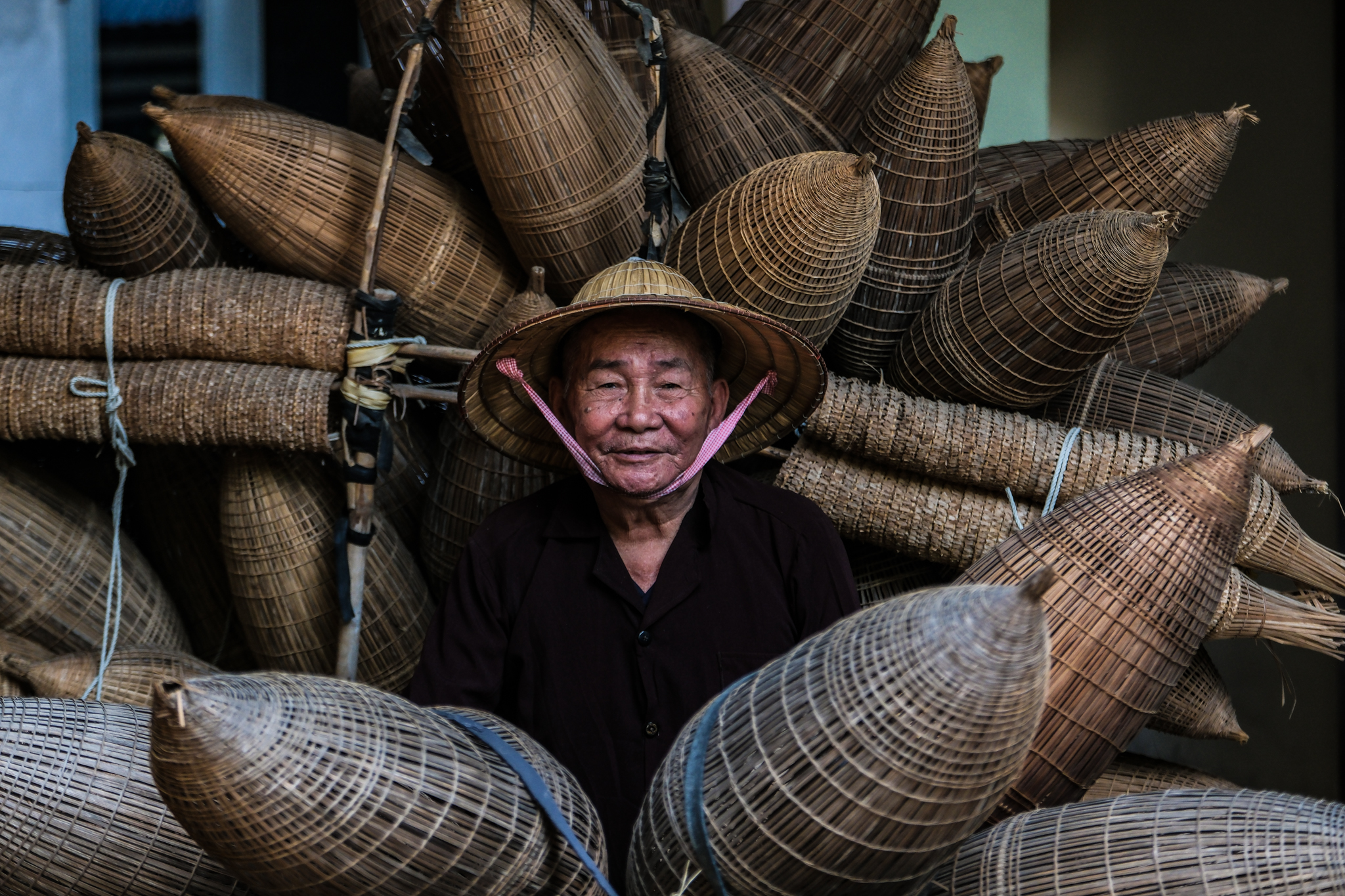 Luong Son Bac, 83, has over 70 years of experience in making bamboo fishing traps. He now retains the job as his hobby in old age and for tourists to see. Photo: Nam Tran / Tuoi Tre News