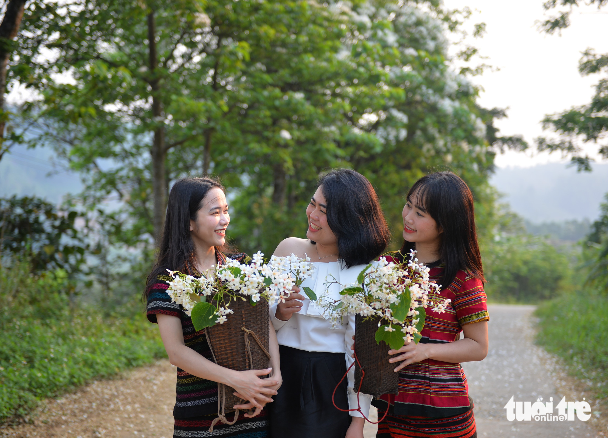 Visitors wear outfits of ethnic minority people while holding bunches of vernicia flowers. Photo: Tuoi Tre