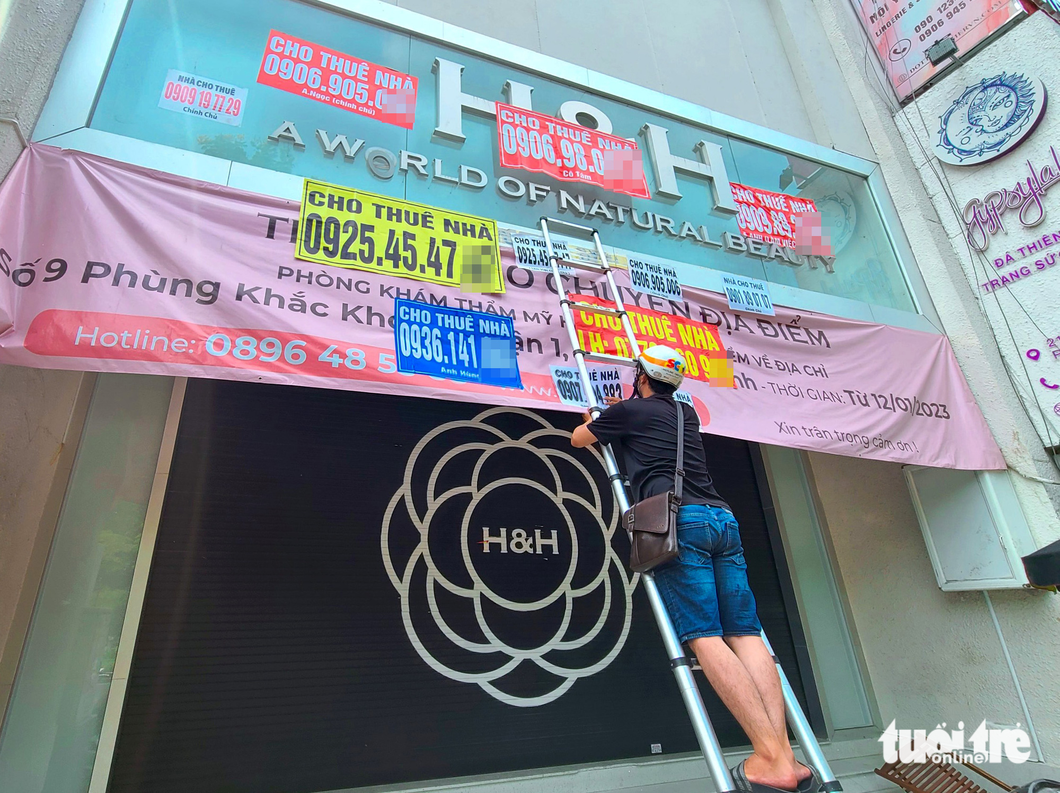 A broker sticks a retail space ad in front of a building on Hai Ba Trung Street in District 1, Ho Chi Minh City.
