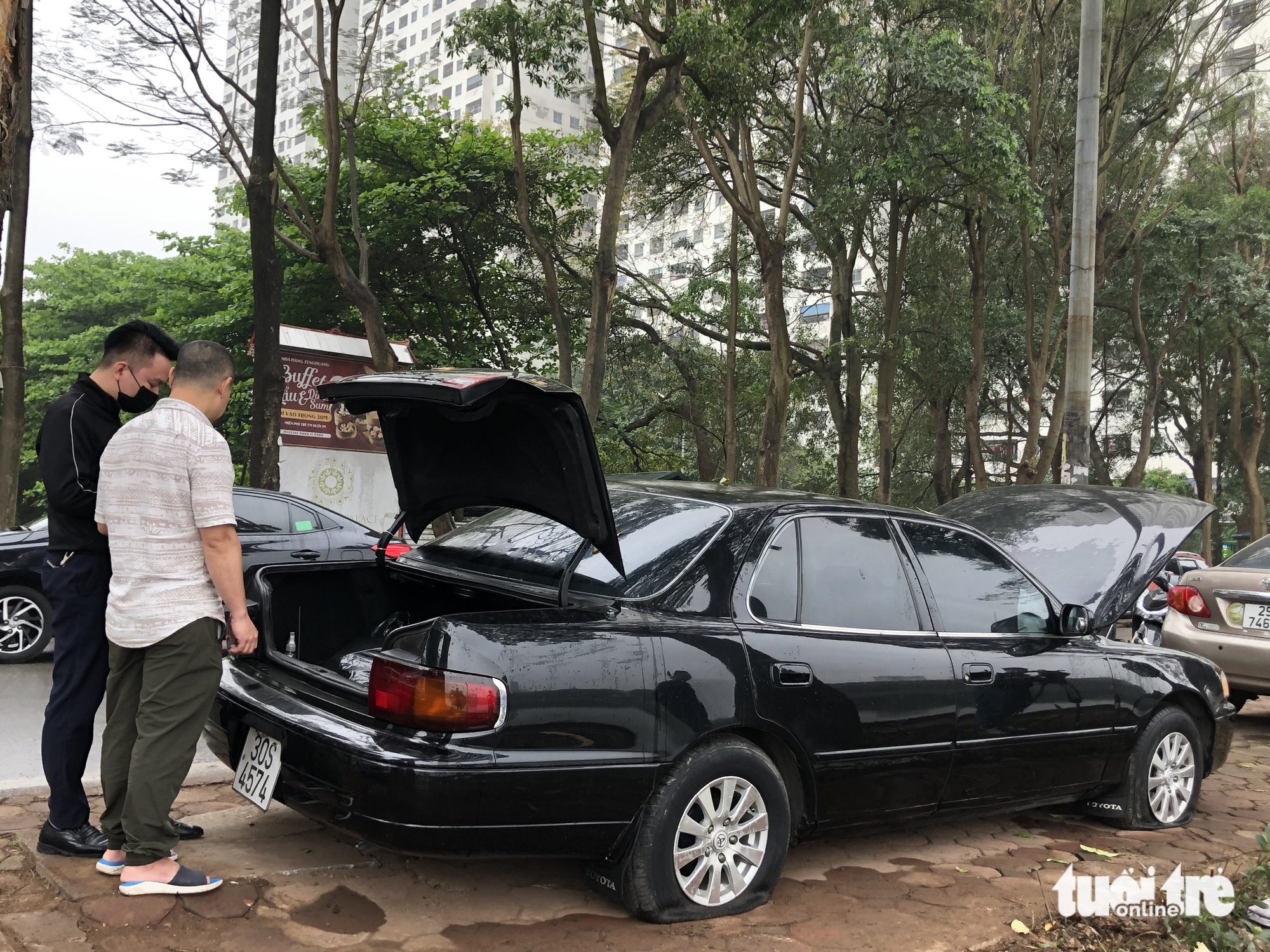 Car owners check their vehicles with punctured tires. Photo: Danh Trong / Tuoi Tre