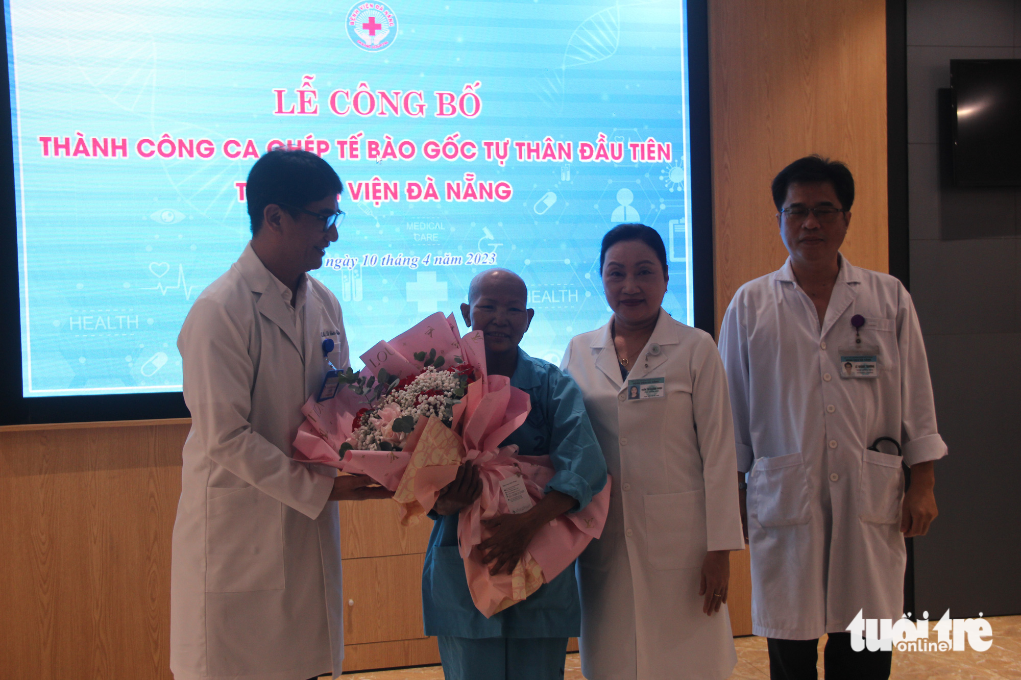 A photo shows Dr Le Duc Nhan (L), director of Da Nang Hospital, giving flowers to the patient receiving autologous therapy. Photo: Truong Trung / Tuoi Tre