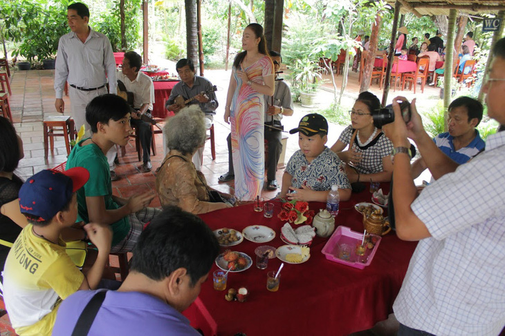 Tourists eat coconut candies and fruits and enjoy Don ca tai tu, a traditional musical art of southern Vietnam, on Phung Islet, Ben Tre Province. Photo: Minh Huyen / Tuoi Tre