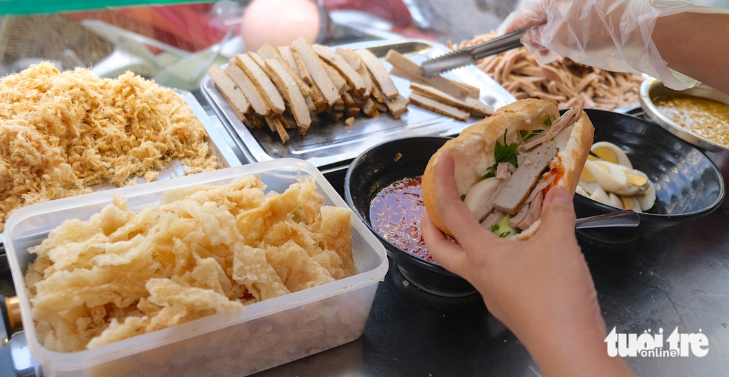 Tram makes the banh mi fillings, such as boiled eggs, steamed Vietnamese ham, stir-fried chili, fried spring rolls, and rice chips, herself. Photo: Ngoc Phuong / Tuoi Tre