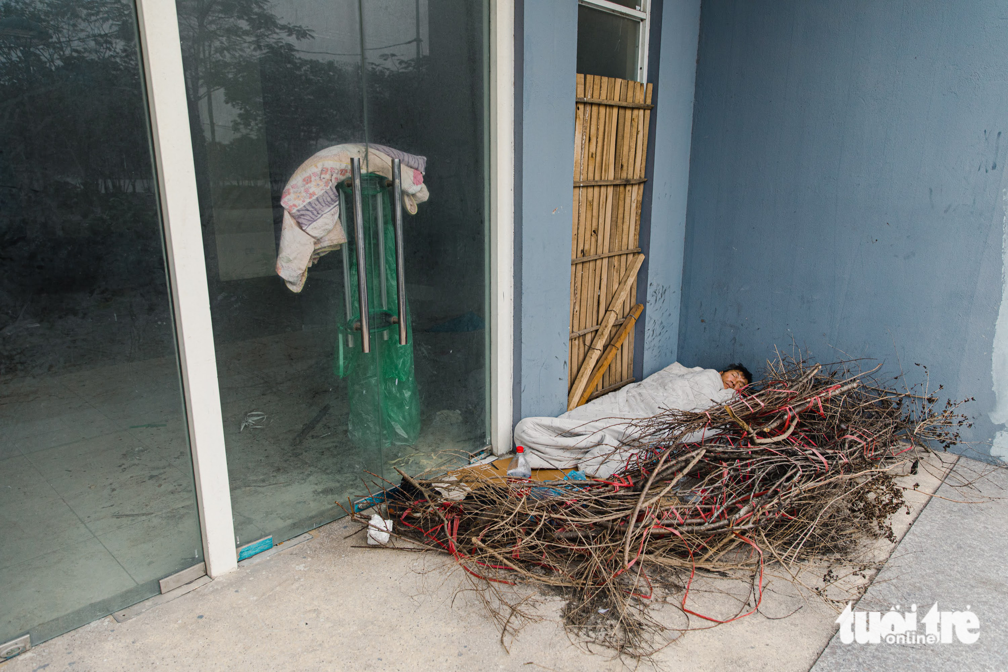 A homeless man sleeps outside a resettlement building in Hanoi. Photo: Tuoi Tre