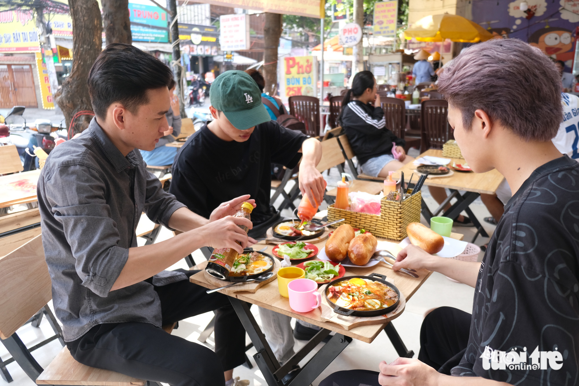 Young men enjoy banh mi chao, priced at VND19,000 at an eatery on Le Duc Tho Street, Go Vap District, Ho Chi Minh City. Photo: Ngoc Phuong / Tuoi Tre