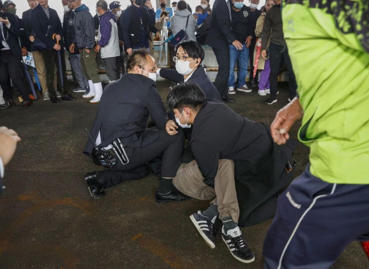 A man, believed to be a suspect who threw a pipe-like object near Japanese Prime Minister Fumio Kishida during his outdoor speech, is held by police officers at Saikazaki fishing port in Wakayama, Wakayama Prefecture, south-western Japan April 15, 2023, in this photo released by Kyodo. Photo: Reuters