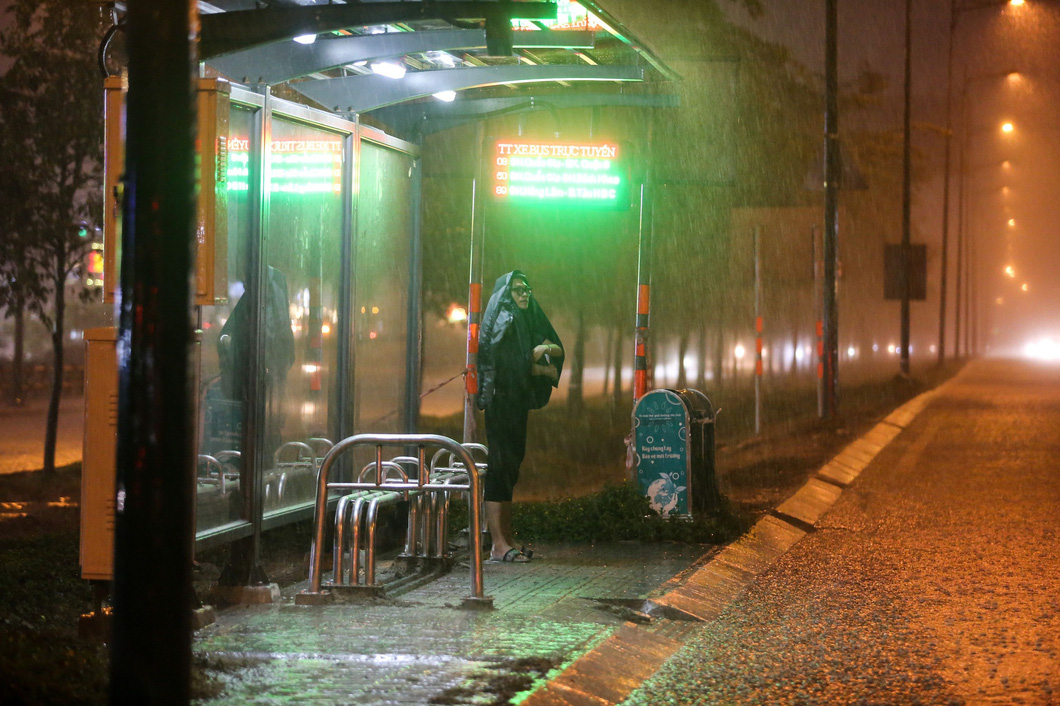 A local resident stands at a bus stop during a heavy rain on Saturday evening in Thu Duc City of Ho Chi Minh City. Photo: Chau Tuan / Tuoi Tre
