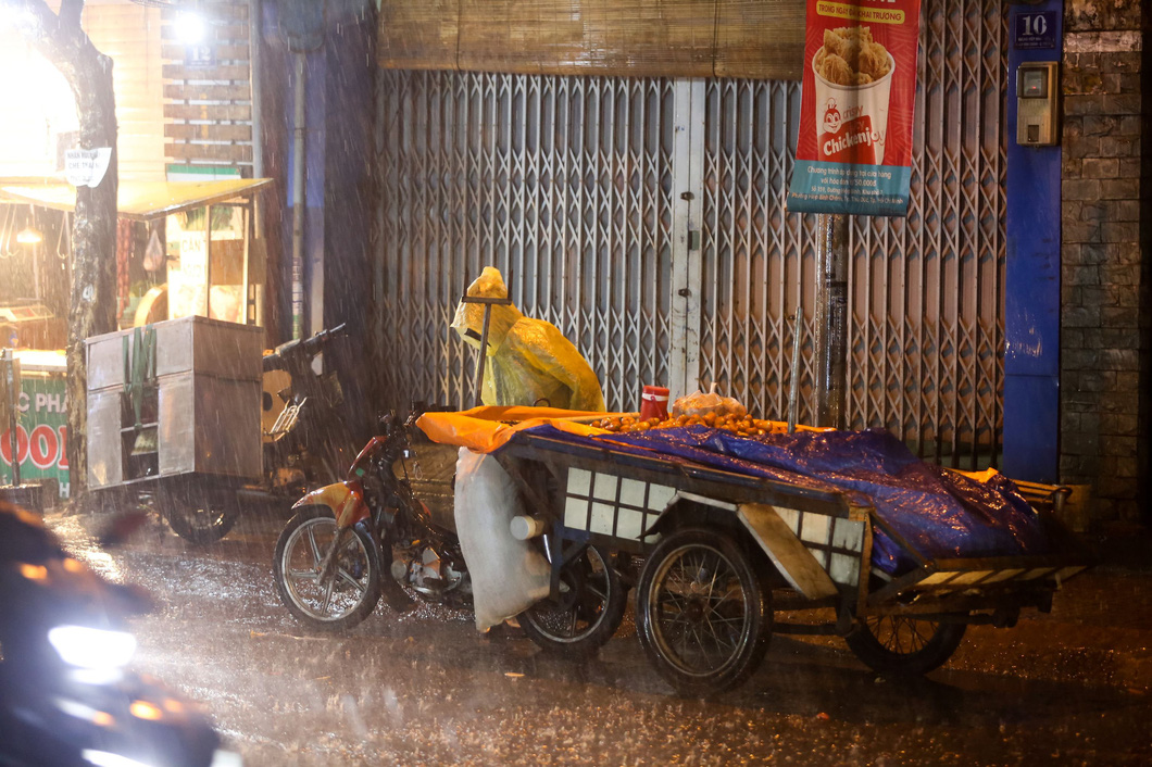 A street vendor wearing a raincoat pulls a fruit cart in a rain on Saturday evening in Thu Duc City of Ho Chi Minh City. Photo: Chau Tuan / Tuoi Tre