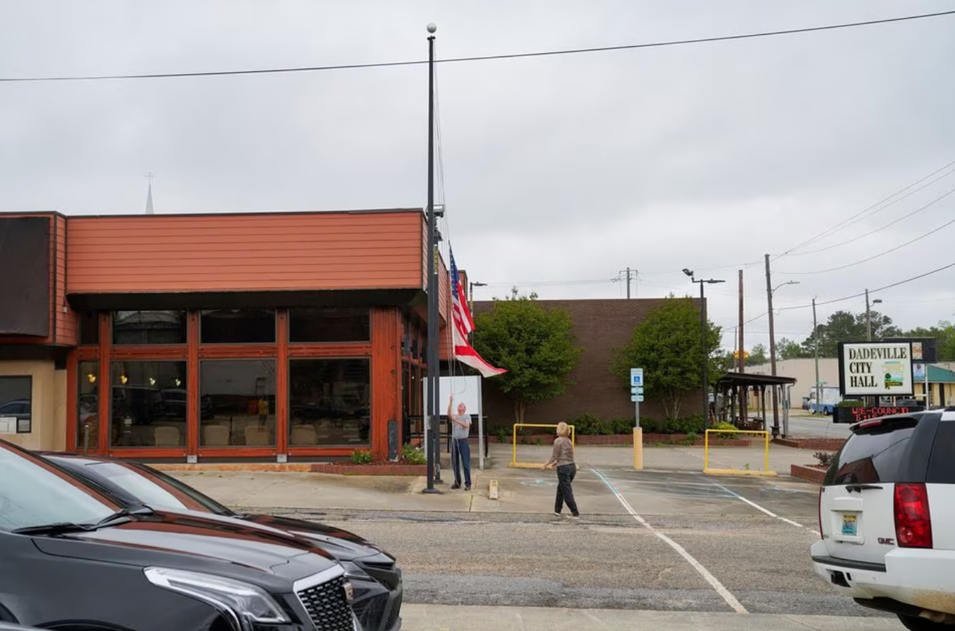 A man lowers the U.S. and Alabama flags to half mast, a day after a shooting at a teenager's birthday party in a dance studio, in Dadeville, Alabama, U.S., April 16, 2023. Photo: Reuters