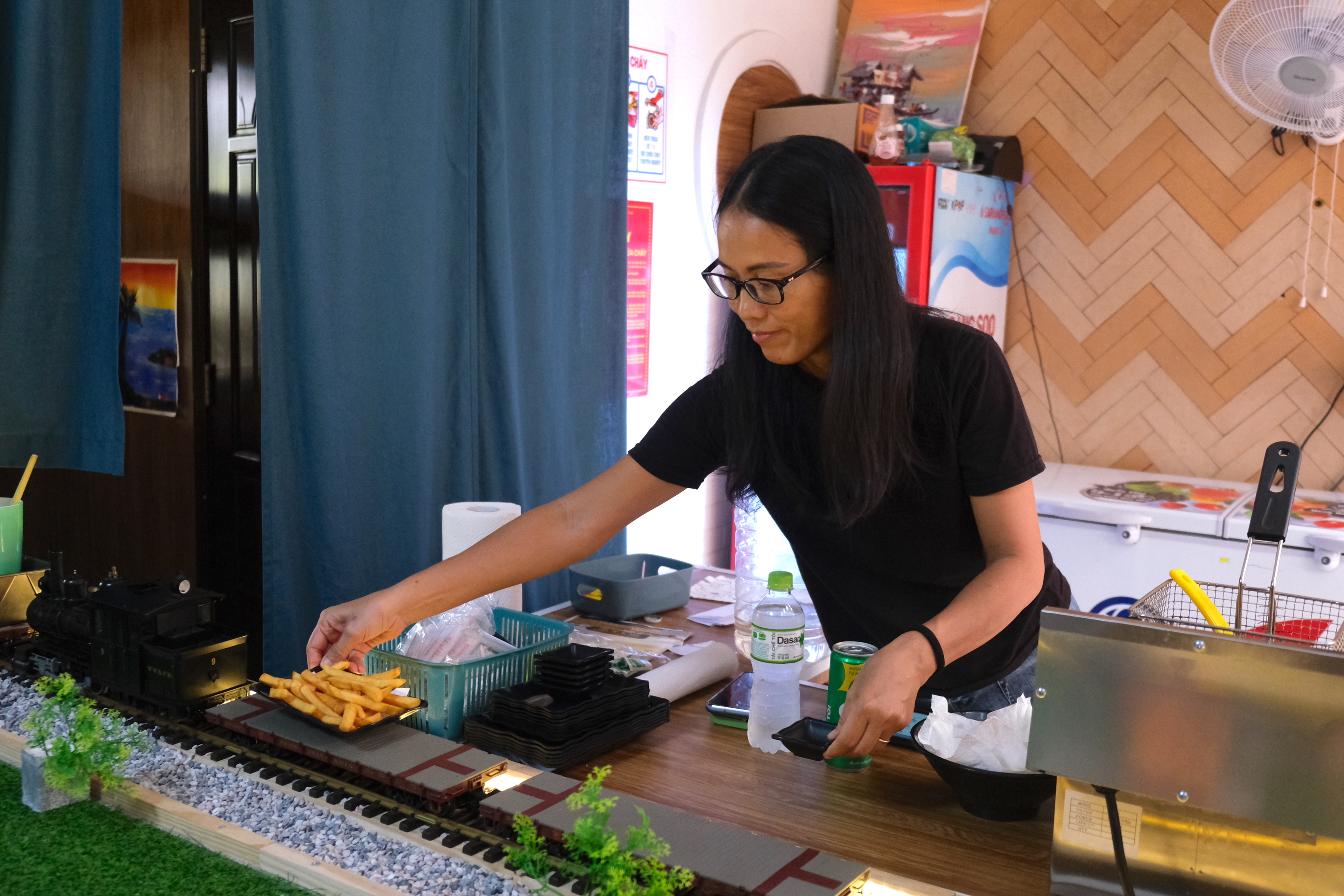 Nguyen Thi Theu, owner of The Train Restaurant puts food on a model train to serve to diners at her restaurant in District 7, Ho Chi Minh City. Photo: Ngoc Phuong / Tuoi Tre News