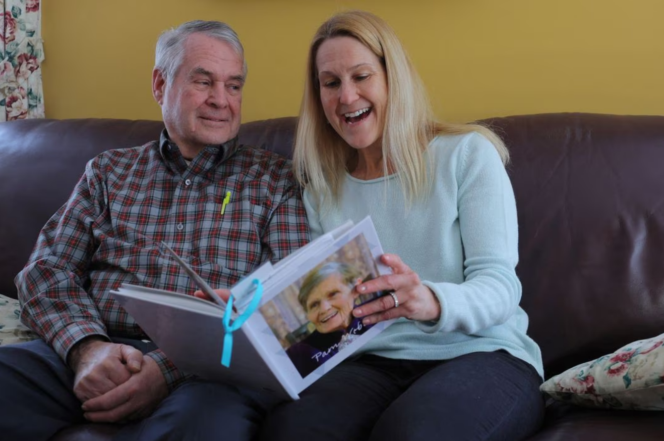 Wendy Nelson looks at an album of family photographs with her father Richard, who has Alzheimer's disease, at his home in Foxborough, Massachusetts, U.S., March 21, 2023. Wendy Nelson's mother and Richard's Webber's wife Pamela, who is on the cover of the photo album, died from Alzheimer's disease, and genetic tests show that Wendy carries two APOE4 gene variants, and her three daughters each carry one APOE4 gene variant, indicating an increased risk of Alzheimer's disease. Photo: Reuters