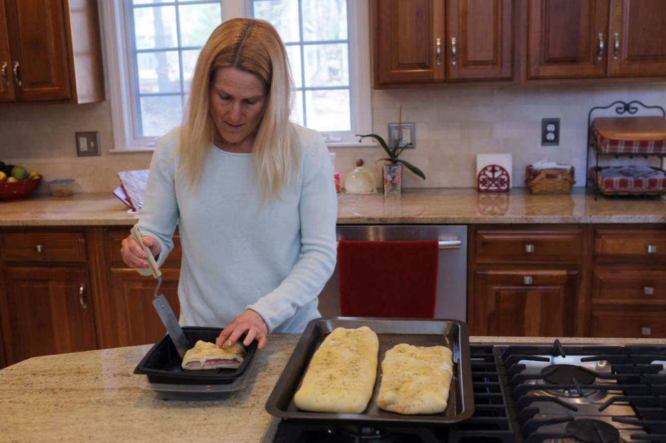 Wendy Nelson prepares a calzone to take to her father, who has Alzheimer's disease and lives in his own home, in Foxborough, Massachusetts, U.S., March 21, 2023. After the death of her mother from Alzheimer's disease, Wendy Nelson took a genetic test and found she carries two APOE4 gene variants, indicating an increased risk of Alzheimer's disease. Photo: Reuters