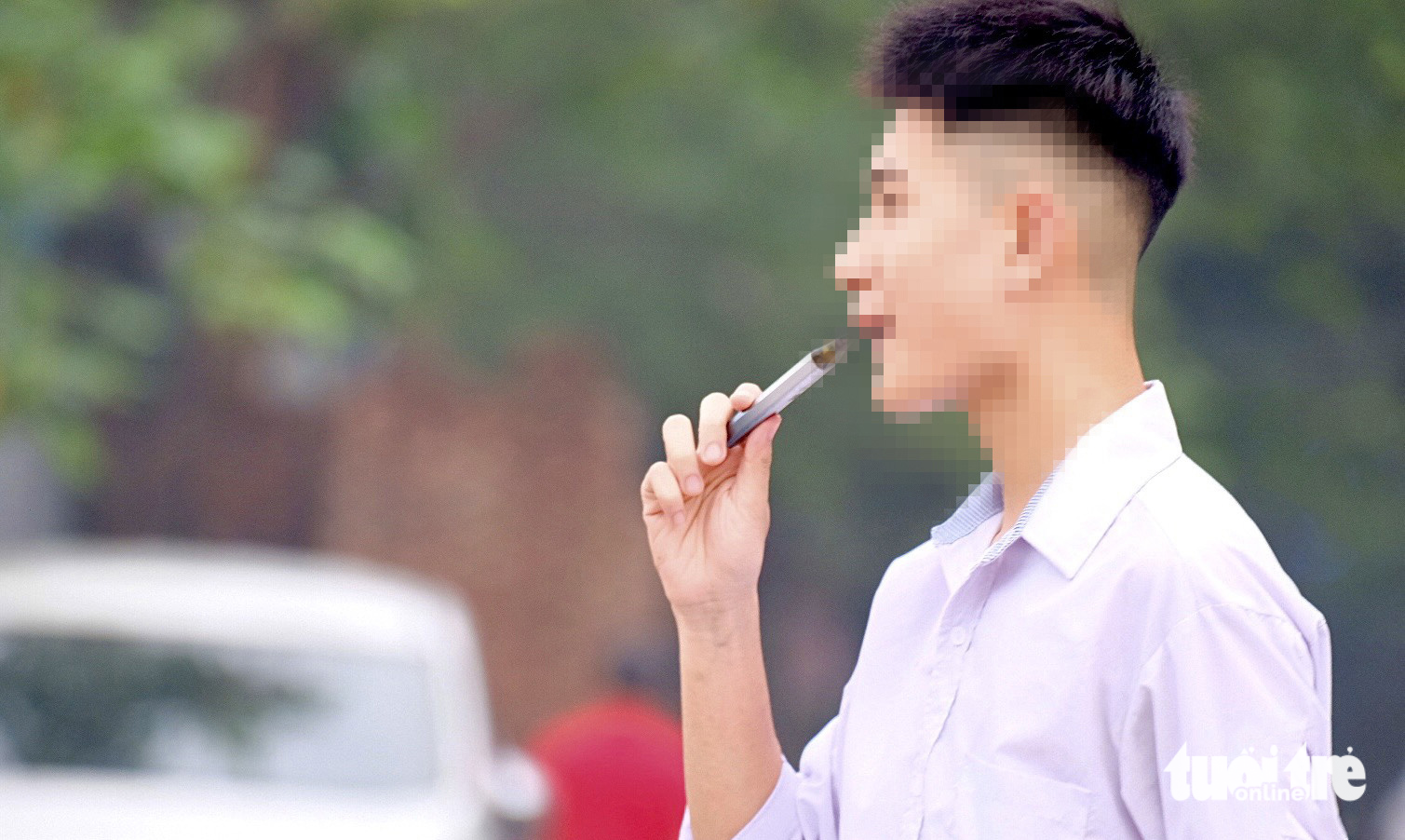 This student grabs an e-cigarette as soon as he walks out of the school gate of a high school in Hanoi city. Photo: Nguyen Bao / Tuoi Tre