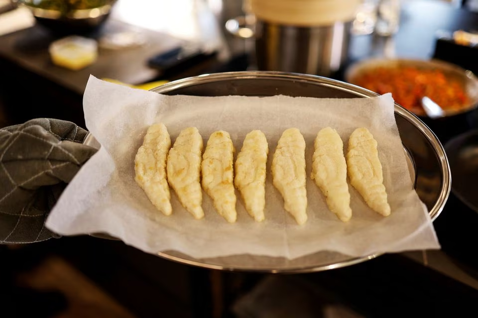 A chef holds up pieces of 3D-printed cultivated grouper fish before making them into a dish for a tasting at the offices of Steakholder Foods in Rehovot, Israel, April 23, 2023. Photo: Reuters