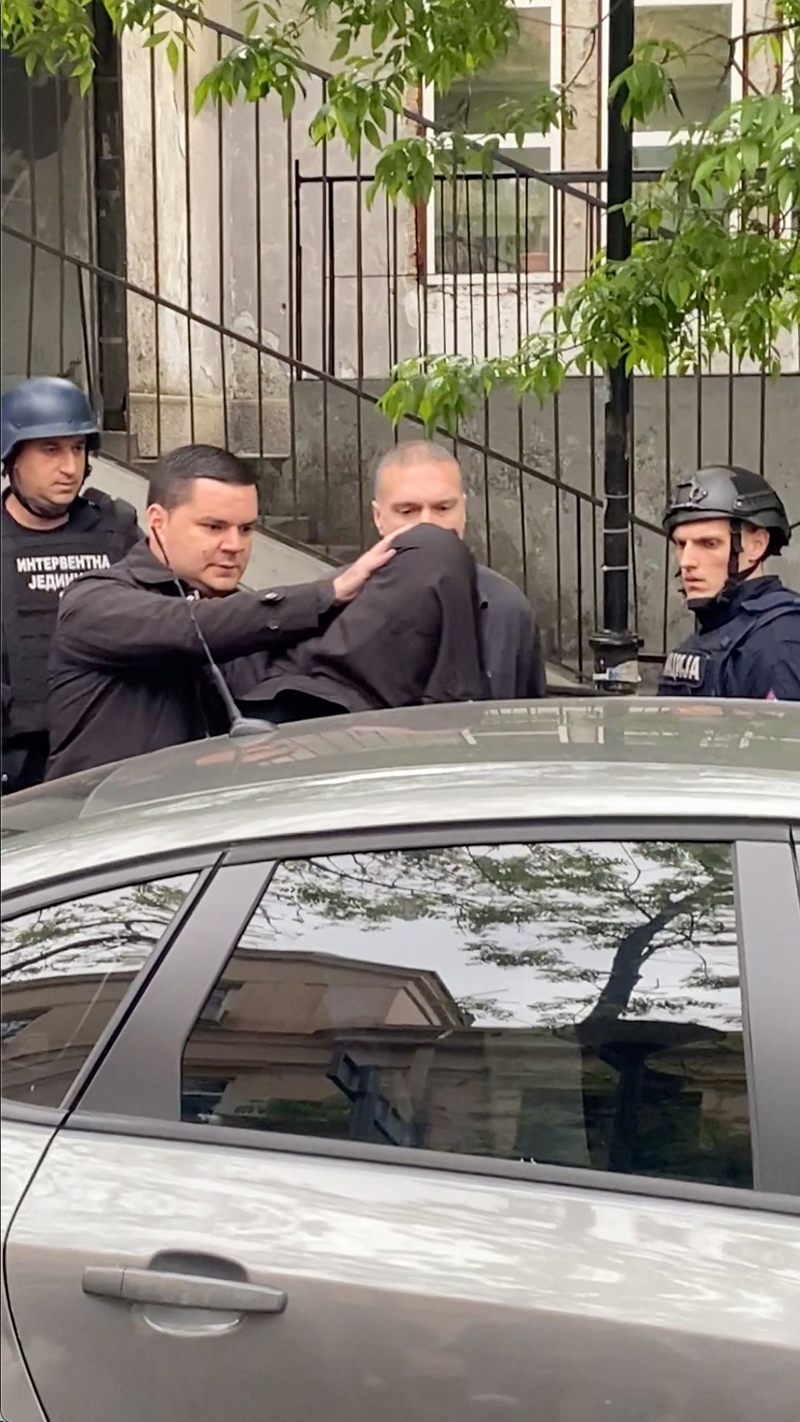 Student arrested after killing nine is led to a police car with head covered by blanket, in Belgrade, Serbia, May 3, 2023, in this screen grab obtained from a social media video. Photo: Reuters