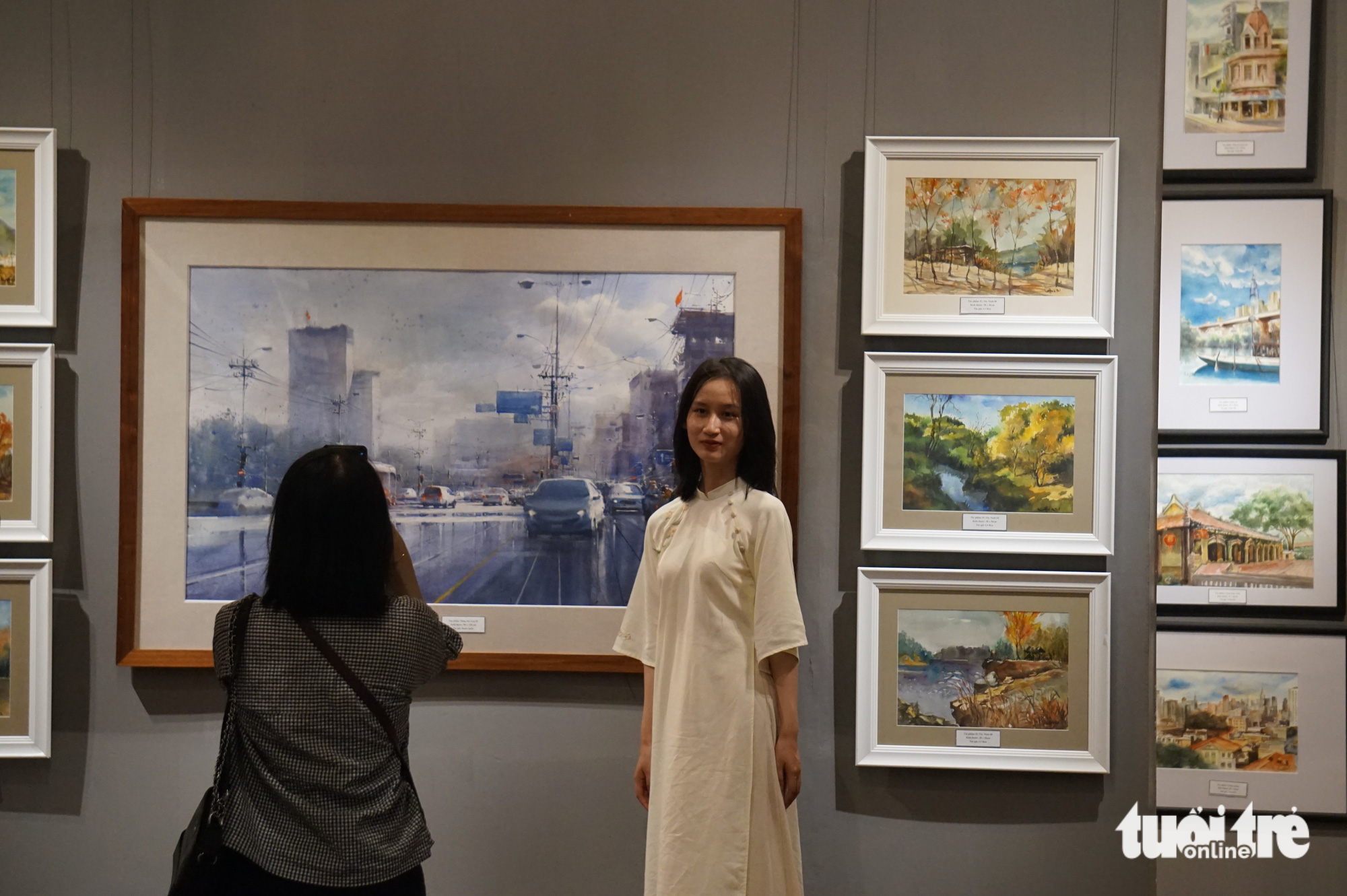 A visitor poses for photos at a watercolor exhibition in Hanoi in May 2023. Photo: T. Dieu / Tuoi Tre