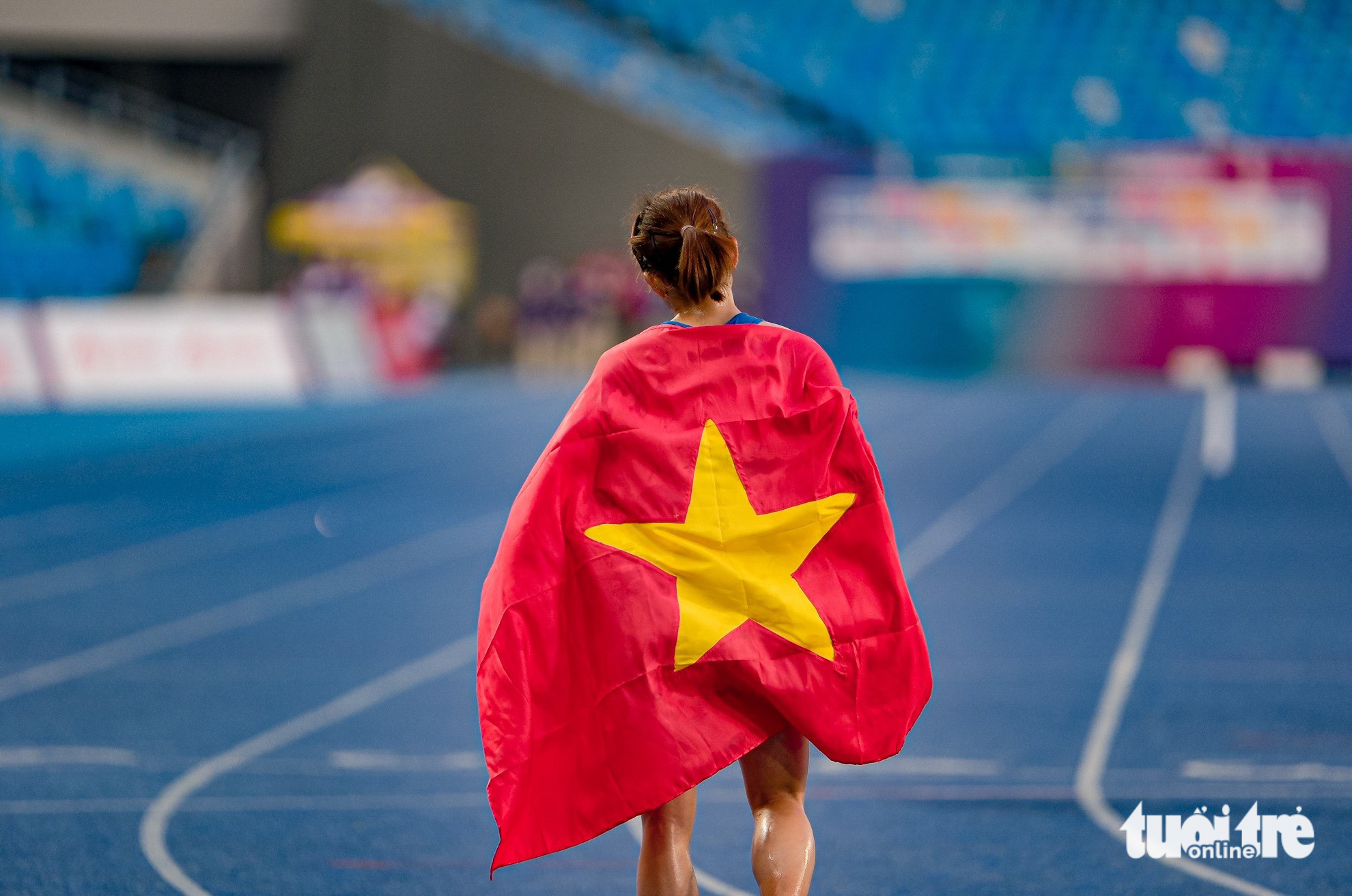 Vietnamese runner Nguyen Thi Oanh proudly wears the national flag after winning gold in the women’s events at the 2023 Southeast Asian Games in Cambodia, May 9, 2023. Photo: Nam Tran / Tuoi Tre