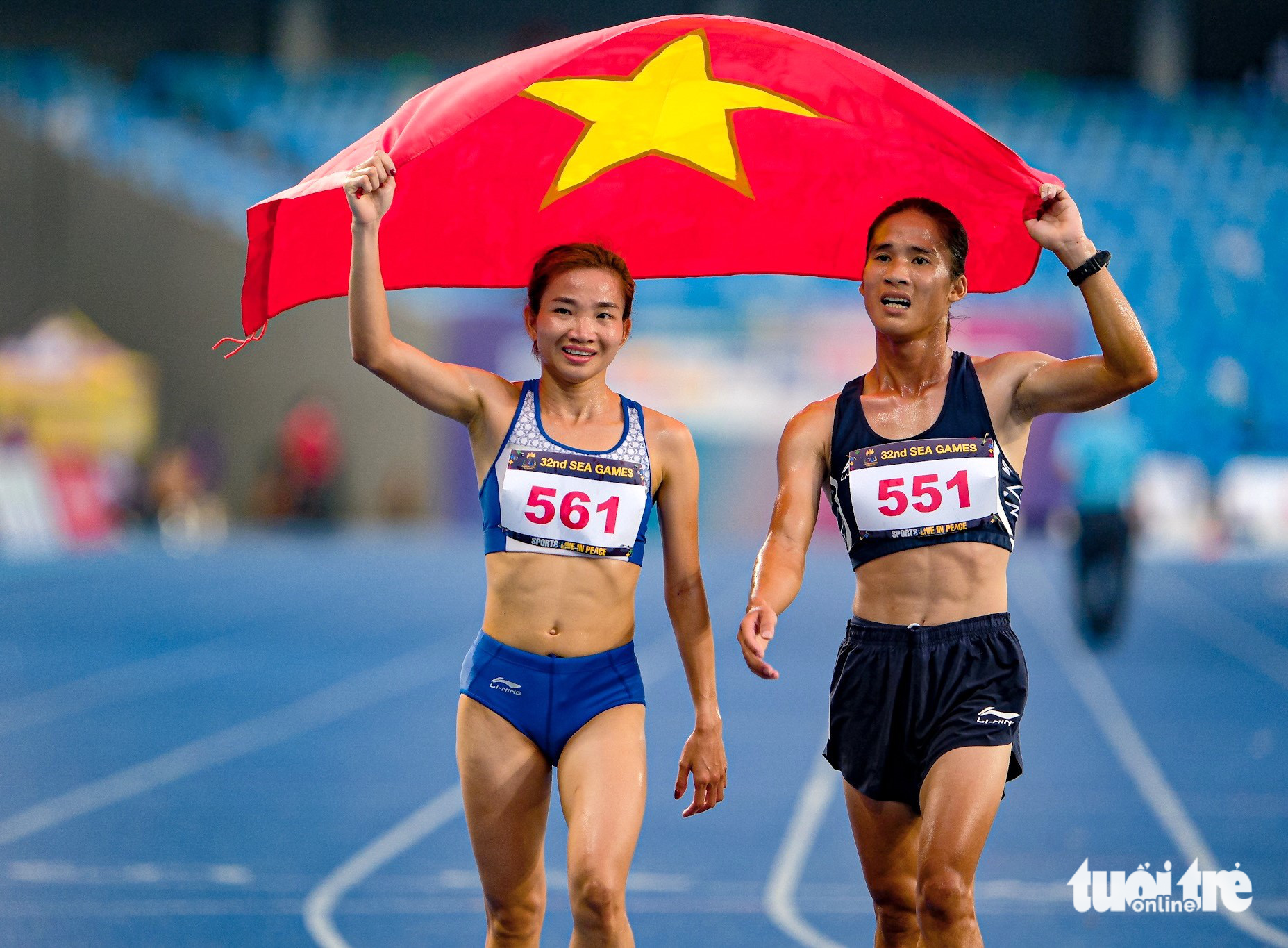 Vietnamese runner Nguyen Thi Oanh (L) beams with joy while wearing the national flag alongside a teammate after they competed in the women's events at the 2023 Southeast Asian Games in Cambodia, May 9, 2023. Photo: Nam Tran / Tuoi Tre