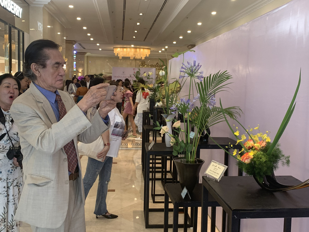 Nguyen Manh Hung, former principal of Hong Bang International University in Ho Chi Minh City takes a photo of flower arrangements at the second Ho Chi Minh City Ikebana exhibition. Photo: Hoai Phuong / Tuoi Tre