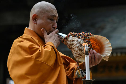 Japanese monk Yoyu Mimatsu blows into a conch at a ritual burning of thousands of paper cranes sent to his Buddhist temple near Hiroshima. Photo: AFP