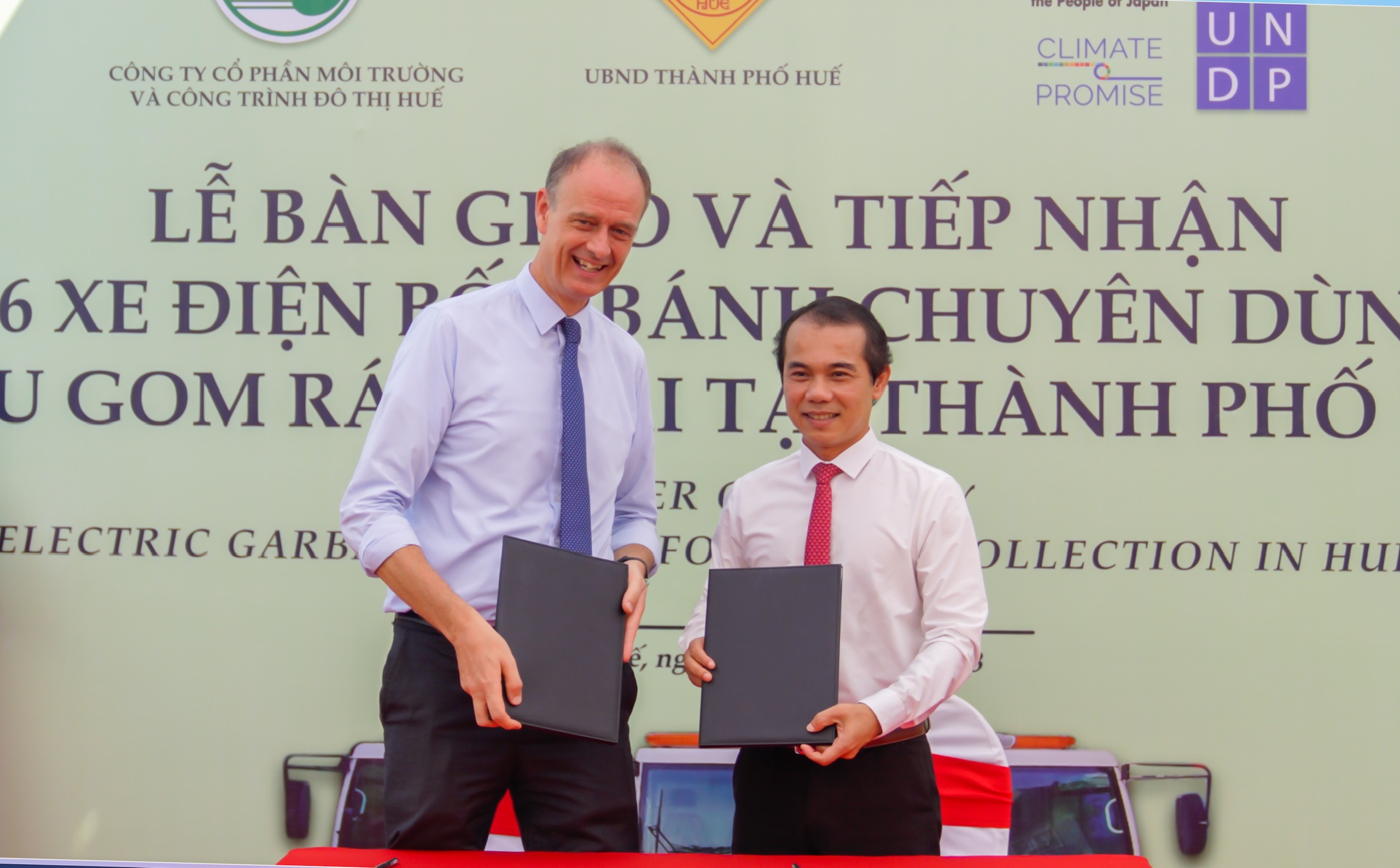 Patrick Haverman (L), UNDP Deputy Resident Representative in Vietnam, and Vo Le Nhat, chairman of the People’s Committee of Hue City, hold the handover records of six electric trucks for waste collection in Hue City, Thua Thien-Hue Province, central Vietnam, May 17, 2023. Photo: UNDP